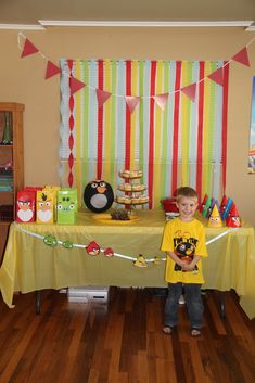 a young boy standing in front of a table with a cake and decorations on it