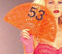 a woman holding an orange fan with the number 53 on it