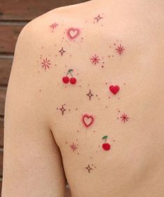 the back of a woman's shoulder with small tattoos on her left arm and chest