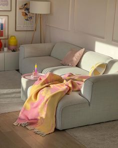 a living room filled with furniture and a blanket on top of the couch next to a coffee table