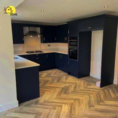 an empty kitchen with wood flooring and black cabinets in the corner, next to a stove top oven