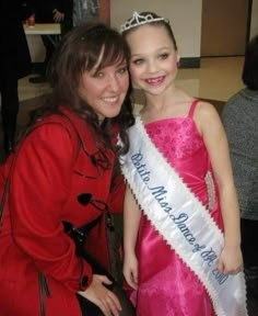 two girls in dresses and tiaras posing for the camera with one girl wearing a pink dress