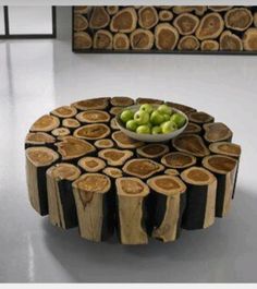 a table made out of tree slices with a bowl of green apples on the top