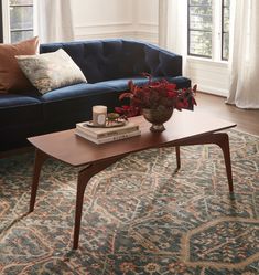 a living room with a blue couch, coffee table and rug in front of it