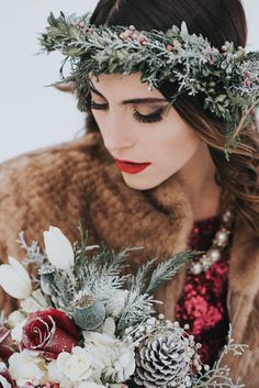 a woman in a fur coat holding a bouquet with flowers and pine cones on her head