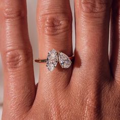 a woman's hand with a ring on it that has two pear shaped diamonds