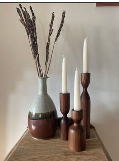 three candles are sitting on a table next to two vases