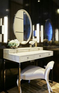 a white chair sitting in front of a vanity with a mirror on top of it