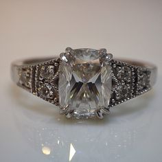 an engagement ring with a square cut diamond in the center and pave set shoulders