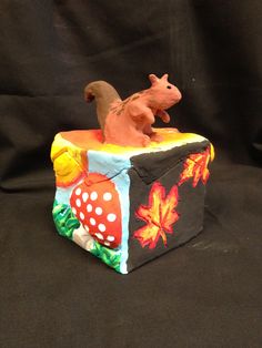 an animal figurine is sitting on top of a box with leaves and mushrooms