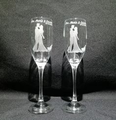 two wine glasses with the bride and groom etched on them, sitting side by side