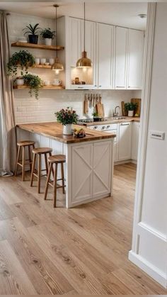 an open kitchen with white cabinets and wooden counter tops, along with two stools in front of the island