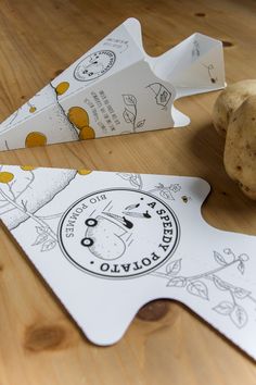 two pieces of paper sitting on top of a wooden table next to a potato peel