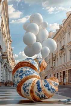 a bunch of white balloons floating in the air over a street with buildings and cars