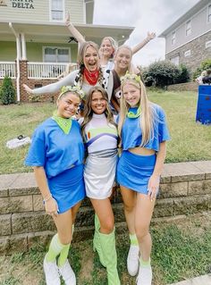 a group of girls standing next to each other in front of a house with their arms up