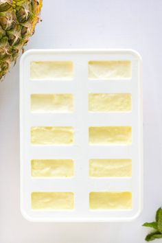 the pineapple is next to an ice tray with cubes of butter on it