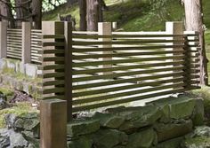 a wooden bench sitting on top of a lush green hillside next to a stone wall