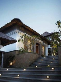 the stairs lead up to an elegant house at dusk with lights shining on the steps