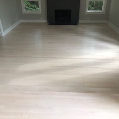 an empty living room with hard wood flooring and two windows in the wall,