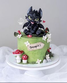 a green cake with a black cat sitting on it's top and mushrooms around the edges