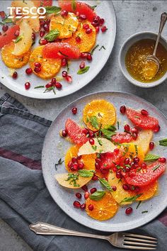 two plates with oranges and pomegranate on them