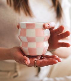 a woman holding a pink and white checkered cup