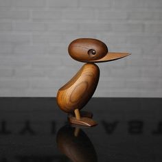 a wooden bird sitting on top of a black table