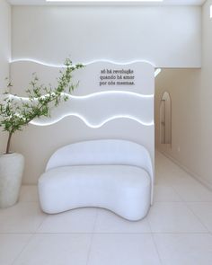 a white couch sitting next to a potted plant on top of a tiled floor