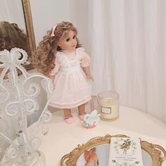 a doll is standing on a table next to a mirror with a card in front of it