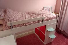 a child's bedroom with pink carpet and white bunk bed, red bookcase under the bed