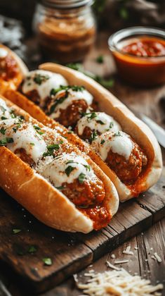 two hotdogs covered in sauce and cheese on a cutting board next to condiments