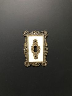 an ornately decorated light switch plate on a black wall