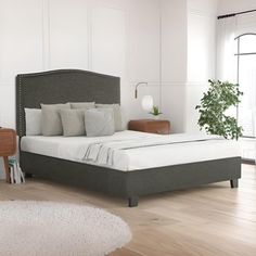 a bedroom with white walls and wood floors, including a bed that has gray linens on the headboard