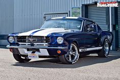 a blue and white mustang parked in front of a building