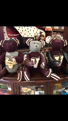 three teddy bears sitting on top of a wooden table in front of a book shelf