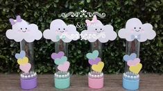 three vases with hearts and clouds in them on a table next to some bushes