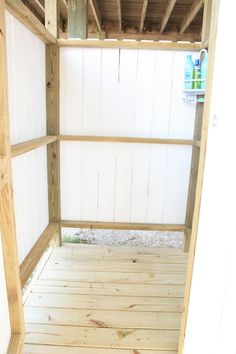 the inside of a shed with wood flooring and white paint on the walls,