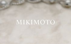 the word mikimoto is written in white on a beige background with silver ornaments