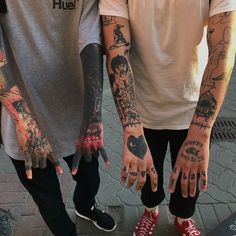 two young men with tattoos on their arms and hands are standing next to each other