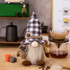 a gnome figurine sitting on top of a wooden table next to coffee cups