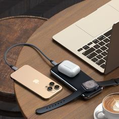 an apple watch, cell phone and other electronics on a table next to a cup of coffee