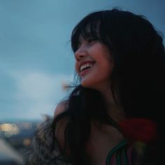 a close up of a person with long hair smiling and looking to the sky at night