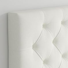 an upholstered white headboard with buttons on the top and bottom part of it