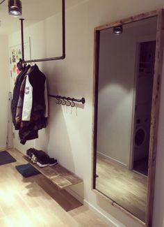 a coat rack with clothes hanging on it next to a mirror