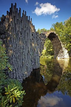 an old stone bridge is reflected in the water