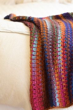 a multicolored crocheted blanket sitting on top of a white couch