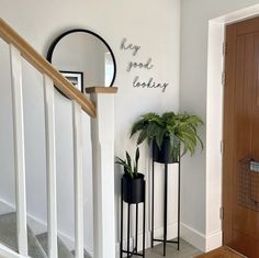 two black planters are on the stairs next to a mirror