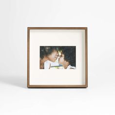 an image of two people kissing in front of a white background with a brown frame