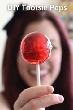 a woman holding up a red lollipop with the words diy tootsie pops on it