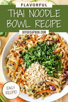 a bowl filled with noodles and vegetables on top of a wooden table next to carrots